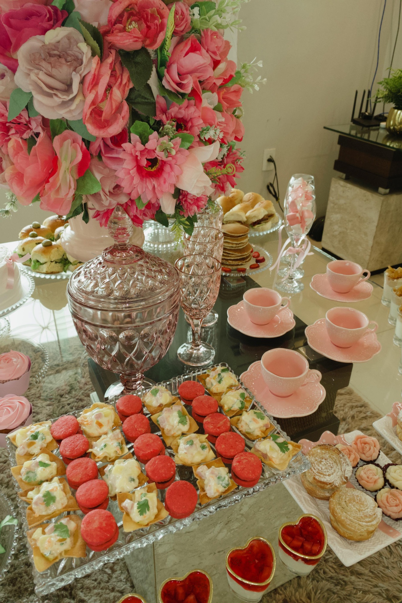 Mesa de chá rosa com flores, salgados e doces