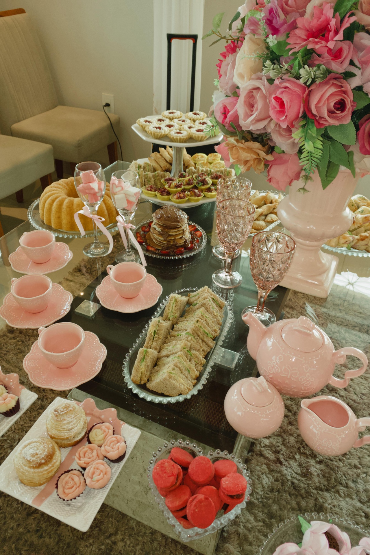 Mesa de chá elegante com sanduíches, bule e flores rosa